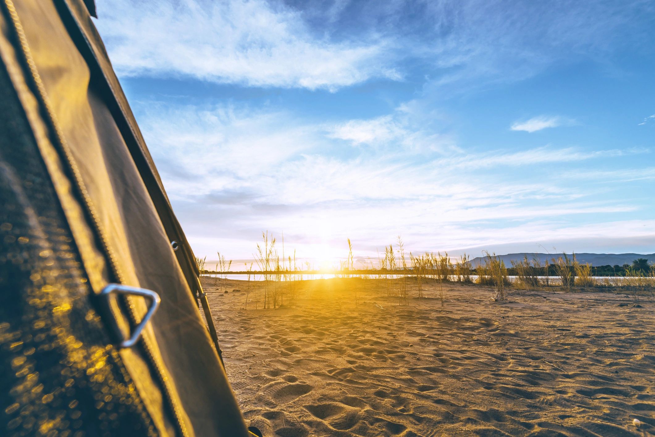 View from a tent toward a campsite at sunset