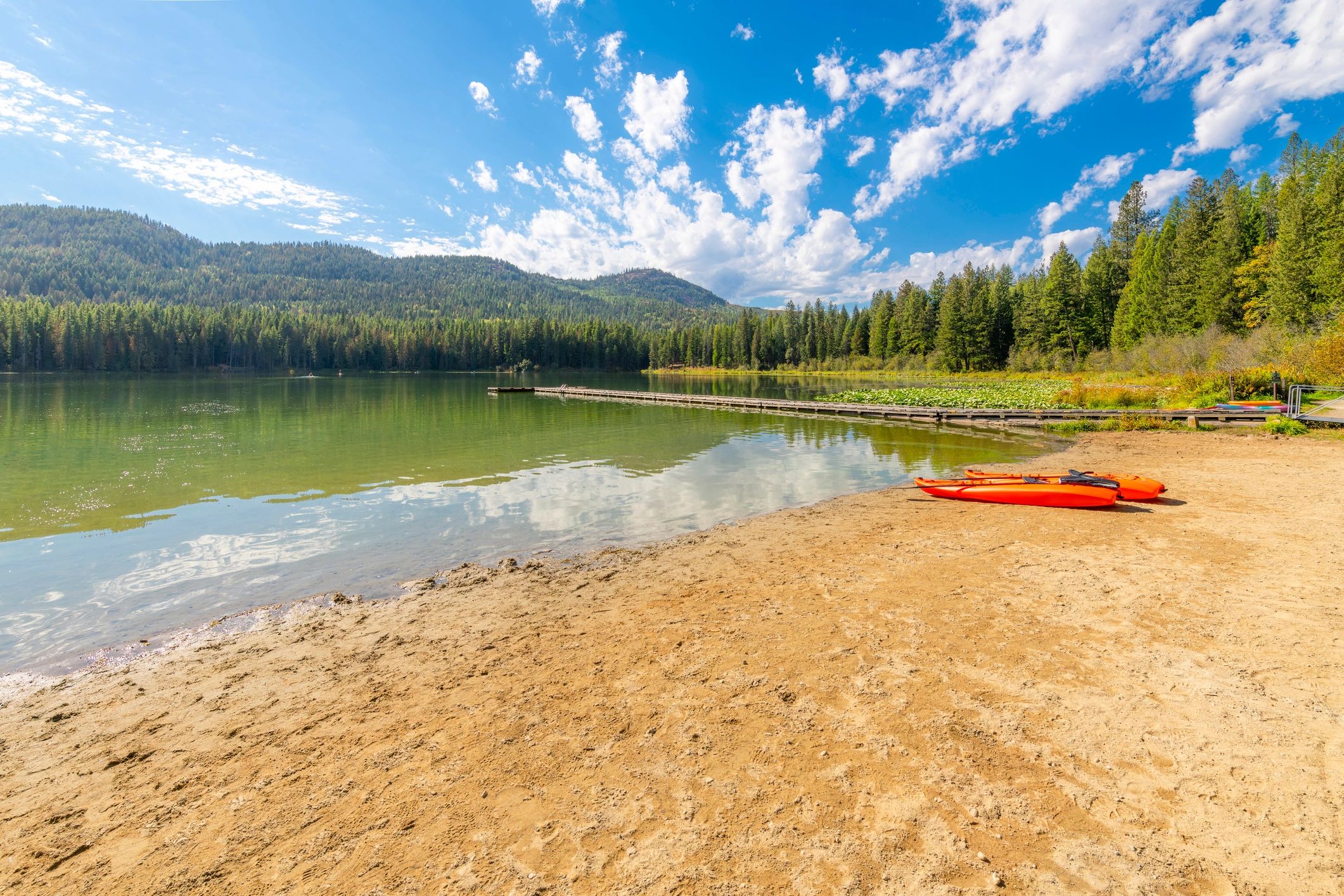 Kayak resting on a sandy lakeshore beside calm water