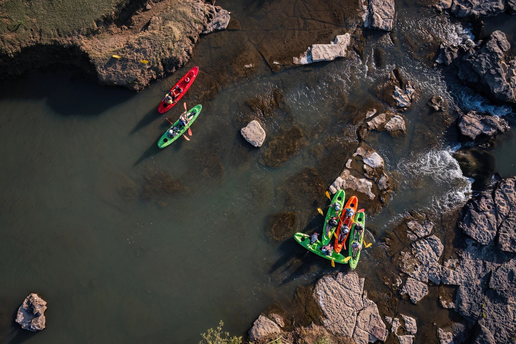 Kayaks gathered on a rocky riverbank
