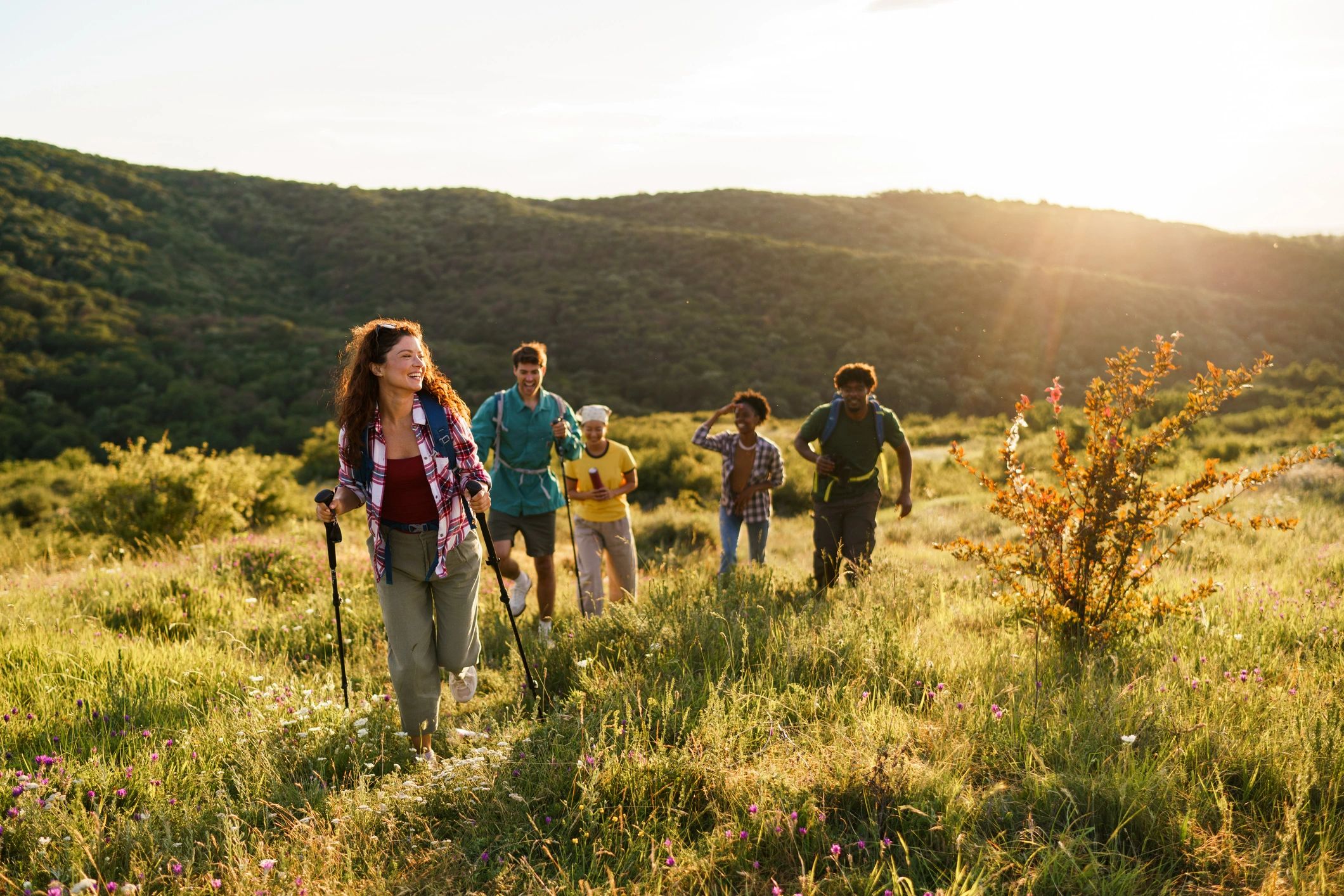 Friends hiking through a grassy field at sunset