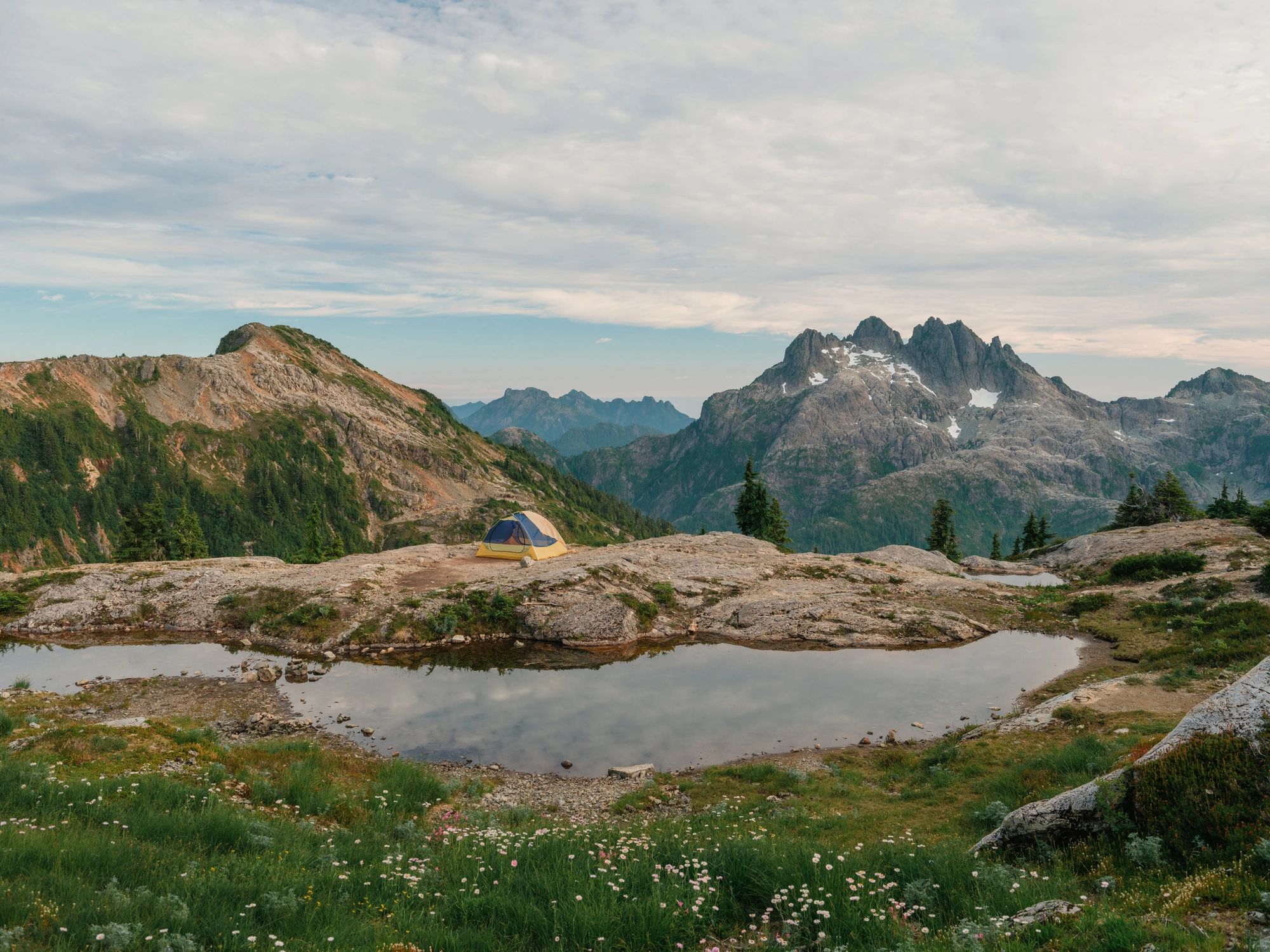 Camping tent beside a calm lake in the wilderness